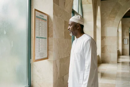 Homme consultant le tableau des horaires de prière dans une mosquée moderne à Annemasse