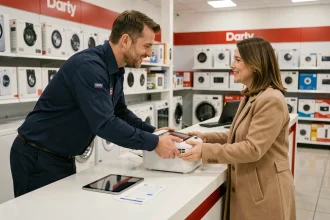Technicien du service client Darty remettant un appareil réparé à une cliente satisfaite au comptoir de service
